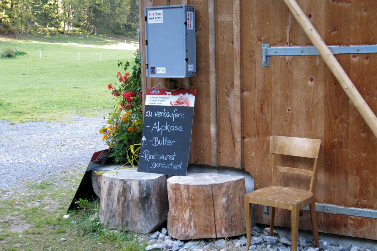 In der Nähe des Lauenensees stosse ich auf eine Besenbeiz, wo ich eine Rindswurst  verspeise. FirstBoxen (über der Tafel) sind überall dort installiert, wo Wanderer und Bikers unterwegs sind. Es sind Erste-Hilfe- und Reparaturset-Stationen.